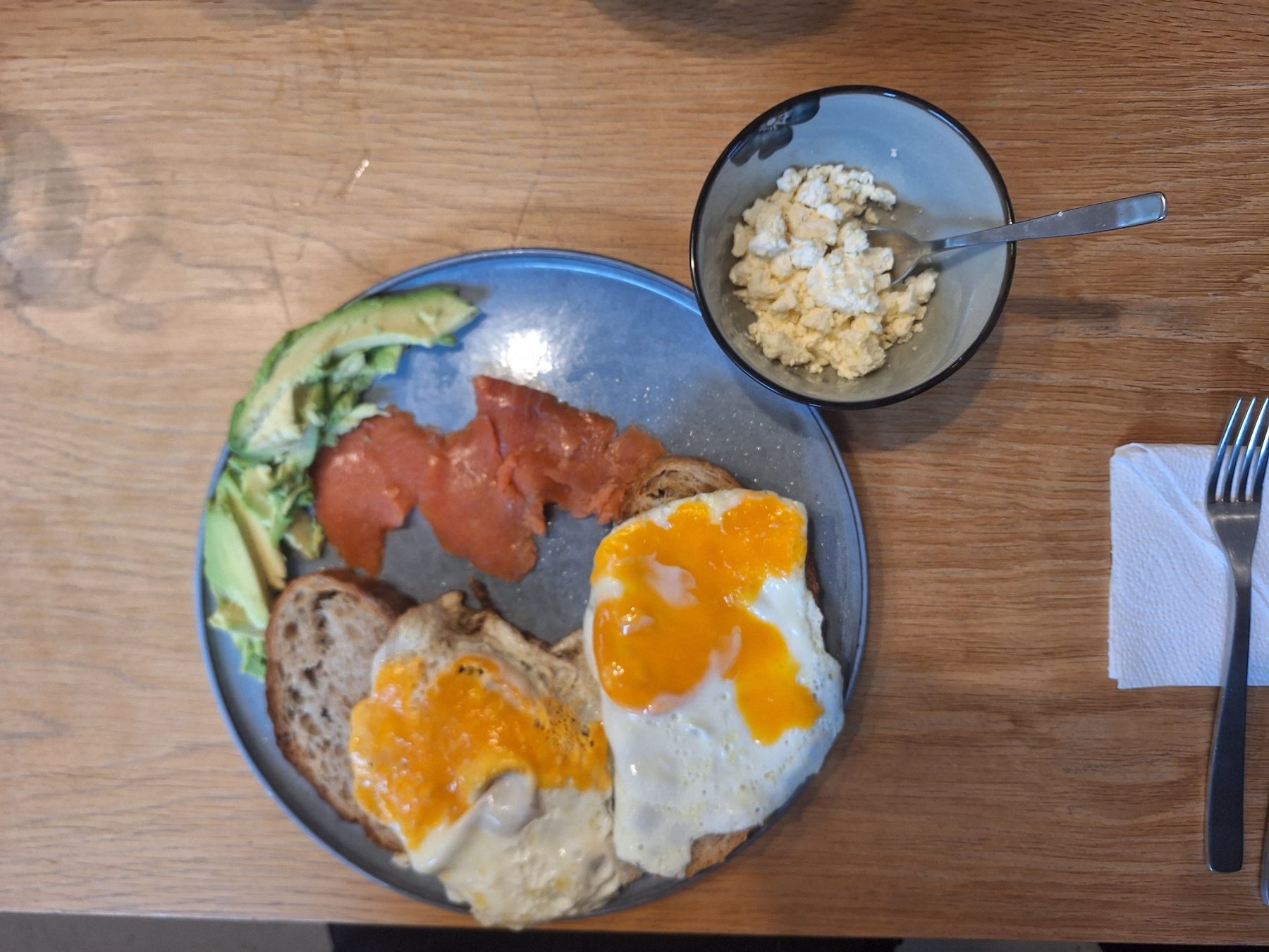 Fried eggs on sourdough with smoked salmon, avocado and a bowl of crumbled feta